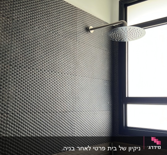 מקלחת עם ראש מקלחת על קיר אריחים כהים